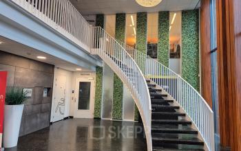 Spacious entrance at Laan van Zuid Hoorn 70, Rijswijk featuring a modern staircase and vibrant decor, ideal for office space rental in a professional building.