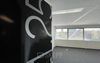 Office space rental at Generaal Eisenhowerplein 111 111 in Rijswijk, featuring a brightly lit room with large windows and numbered black door, ideal for creating a productive work environment.