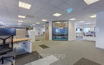 Modern office space for rent at Patrijsweg 62, Rijswijk, featuring open floorplan with workstations and a glass-walled conference room.