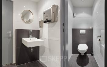 Rijswijk office space rental at Patrijsweg 62, featuring a modern restroom with sleek fixtures and tiled surfaces.