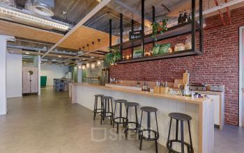 Furnished office space at Patrijsweg 62, Rijswijk, featuring a modern lounge area with a long counter and bar stools, exposed ceilings, and decorative lighting.