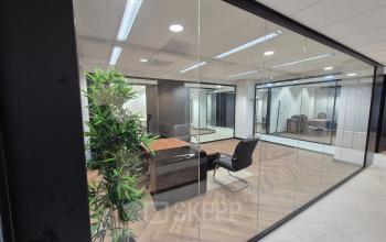 Glass-walled office at JC van Markenlaan 3 in Rijswijk showcasing a stylish meeting area with wooden flooring and contemporary furniture, perfect for office space rental.