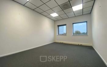 Bright office space for rent at Noordhoven 19, Roermond, featuring two windows with ample natural light and a simple yet functional design.