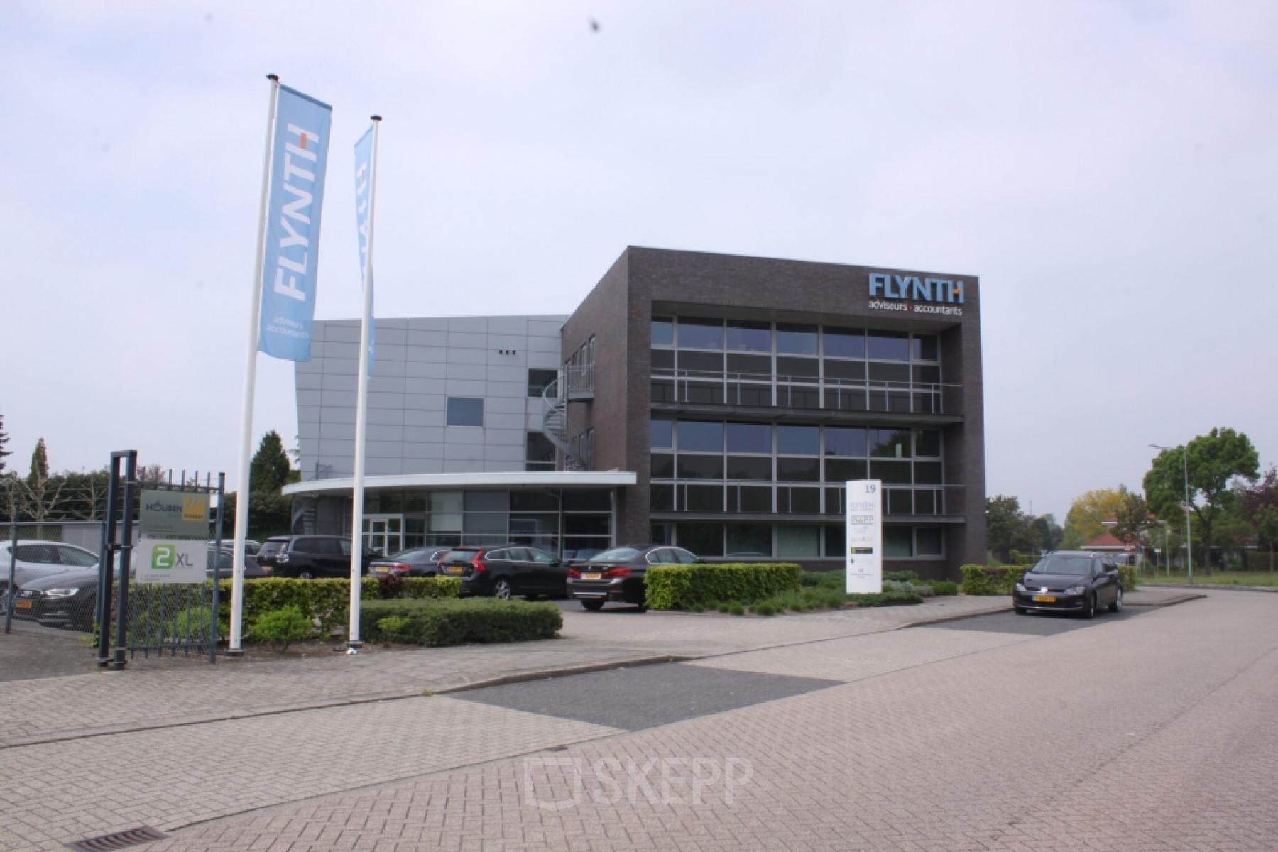 Exterior view of the office building at Noordhoven 19 in Roermond, featuring modern architecture and ample parking. Ideal location for office space rental.