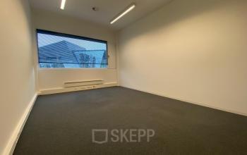 Spacious, unfurnished office space with carpet flooring and a large window offering natural light at Boven de Wolfskuil 3, Roermond. Ideal for businesses seeking office space rental.