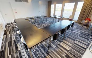 Conference room available for office space rental at Boven de Wolfskuil 3, Roermond, featuring a U-shaped table setup with modern chairs and large windows for natural light.