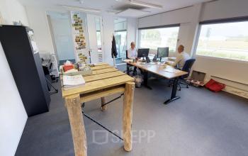 Furnished office space at Boven de Wolfskuil 3, Roermond, featuring two people engaged in work at desks.