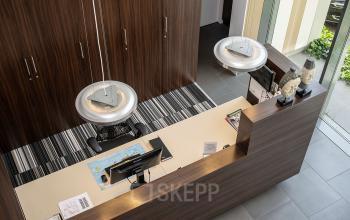 Modern reception area with wooden desk and pendant lighting, suitable for office space rental at Boven de Wolfskuil 3 in Roermond.