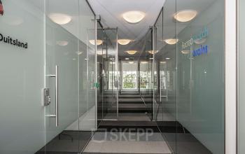Modern glass-walled corridor in an office to rent at Boven de Wolfskuil 3, Roermond, with natural light streaming through at the end.