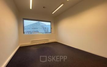Unfurnished office space with a large window and carpet flooring at Boven de Wolfskuil 3, Roermond, available for office space rental.