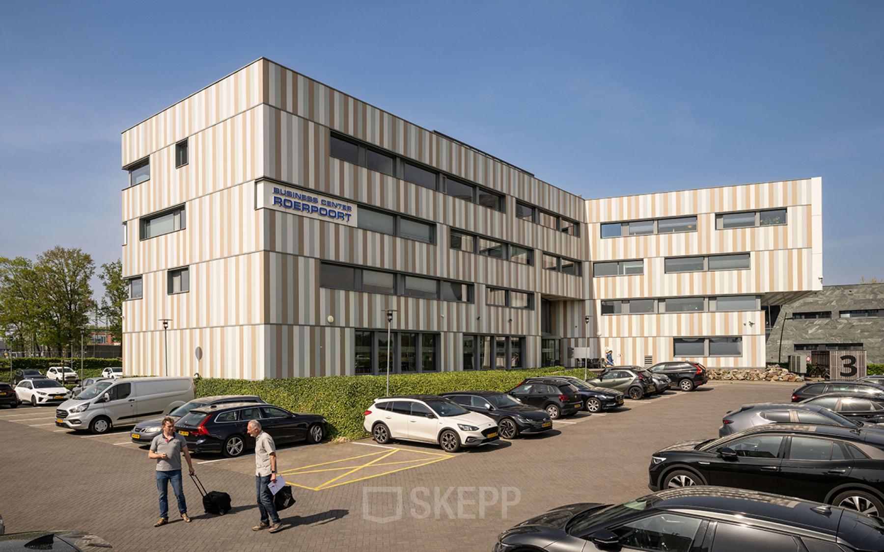 Exterior view of the office building at Boven de Wolfskuil 3, Roermond with several parked cars and a couple of people talking in the parking area.