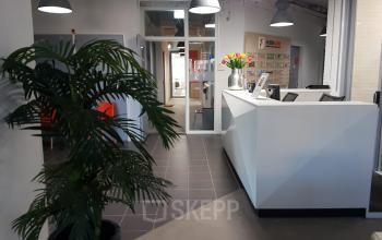 Modern reception area at Corkstraat 46 offering office space rental, with a welcoming desk, stylish seating, and vibrant plant life in Rotterdam Airport area.