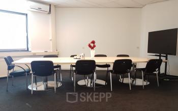 Modern conference room at Corkstraat 46, office space rental with a large table, chairs, and presentation TV in Rotterdam Airport.