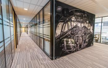 Interior office space at Rotterdam Airportplein 22 featuring glass walls and unique cockpit wall art, ideal for dynamic office space rental.