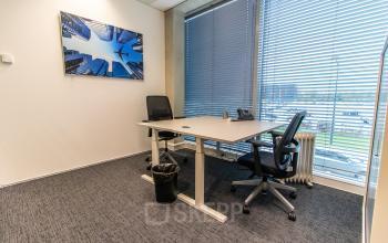 Furnished office space rental at Rotterdam Airportplein 22 featuring two desks, office chairs, large windows, and modern decor. Ideal for businesses seeking an office to rent.