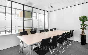 Conference room at Rotterdam Airportplein 22 featuring a long table with black chairs arranged neatly, ideal for office space rental.