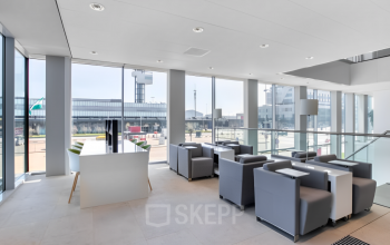 Brightly lit office space for rent at Rotterdam Airportplein 22, featuring modern furnishings and large windows with scenic airport views.