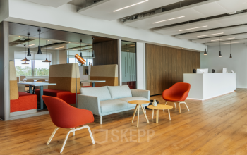 Modern office space for rent in Rotterdam Alexander with a stylish lounge area, featuring colorful chairs and wooden tables; perfect for casual meetings or relaxation.