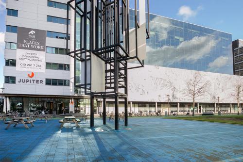 Exterior view of the office building at Prins Alexanderplein 5, Rotterdam Alexander, showcasing modern architecture with reflective glass surfaces and outdoor seating. Ideal for those seeking an office space rental in a vibrant location.