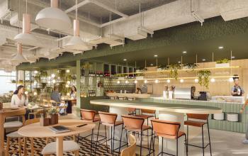 Modern office space with individuals enjoying snacks and drinks at a stylish pantry area in Rotterdam Alexander, ideal for office space rental opportunities.