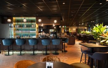 Elegantly furnished office lounge with bar seating and lush green plants at George Hintzenweg 77-89, ideal for rent office space in Rotterdam Alexander.