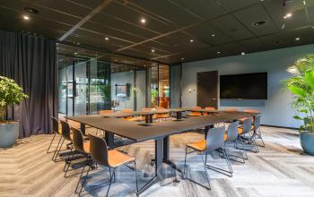 Modern conference room at George Hintzenweg 77 - 89 in Rotterdam Alexander, featuring a large meeting table with chairs and a wall-mounted screen, perfect for office space rental.
