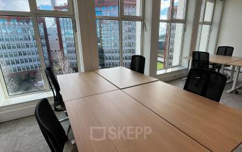 Bright office space with large windows overlooking Rotterdam Alexander, furnished with desks and chairs, ideal for office space rental.