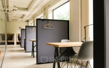 Modern workspaces at Marten Meesweg 8-10, Rotterdam Alexander, featuring individual desks with chairs, dividers, and hanging racks in a well-lit office to rent.