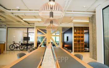Modern office space with long communal work table, stylish lighting fixtures, and glass partitioned rooms at Marten Meesweg 8-10 in Rotterdam Alexander.
