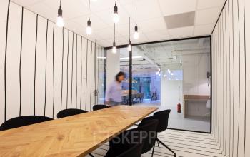 Modern office space rental at Marten Meesweg 8-10, Rotterdam Alexander, with wooden meeting table, black chairs, and glass partition.