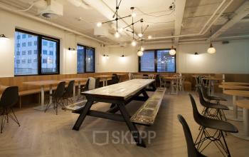 Modern office space with a large communal table and surrounding chairs located at Marten Meesweg 8-10, in Rotterdam Alexander. Stylish lighting fixtures and ample natural light create a welcoming atmosphere.