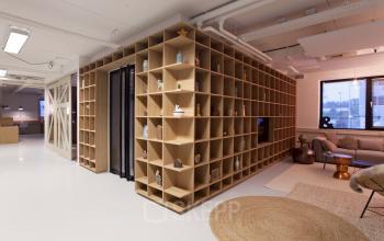 Interior of office to rent at Marten Meesweg 8-10, Rotterdam Alexander, featuring a wall of shelves with decorations, a sitting area with a sofa, and large windows.