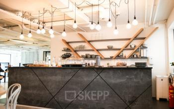 Modern office pantry at Marten Meesweg 8-10, Rotterdam Alexander with stylish counter, shelving, and hanging lights for office space rental.