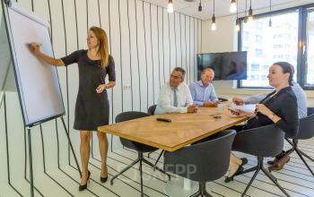 Office space rental at Marten Meesweg 8-10 in Rotterdam Alexander, featuring a meeting room with a modern table, people engaging in a business meeting, flat screen for presentations.