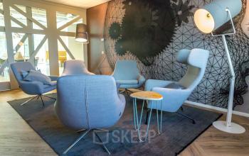 Comfortable lounge area in an office space rental at Marten Meesweg 8-10, Rotterdam Alexander. Features modern gray chairs, stylish black accent wall, and contemporary lighting.