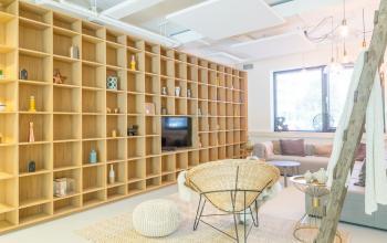 Bright and stylish lounge area with a large wooden bookshelf, comfortable seating, and decorative items, located at Marten Meesweg 8-10 in Rotterdam Alexander.