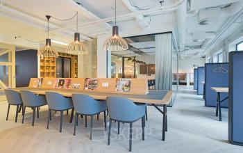 Modern office space to rent at Marten Meesweg 8-10, Rotterdam Alexander, featuring a long table with blue chairs, hanging lights, and open shelving.