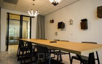 Modern conference room at Marten Meesweg 8-10, Rotterdam Alexander, with long wooden table, black chairs, and decorative wall fixtures.