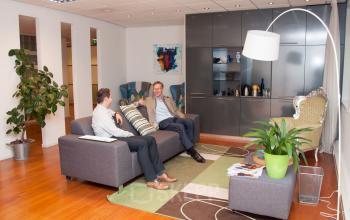 Comfortable office lounge at Hoofdweg 66, Rotterdam Alexander, with modern furnishings, two men discussing business on the sofa.