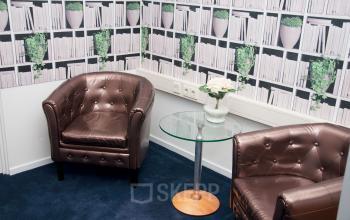 Cozy corner of an office with two brown leather armchairs, a glass coffee table, and decorative shelves wallpaper at Hoofdweg 66, Rotterdam Alexander, office space rental.