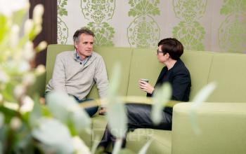 Two business professionals having a discussion on a green couch in a furnished office lounge at Hoofdweg 66, Rotterdam Alexander, Rotterdam.
