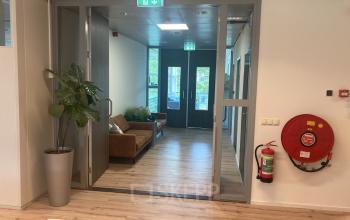 Interior entrance hallway of an office space at Hoofdweg 66, Rotterdam Alexander, featuring a brown sofa and green plants.