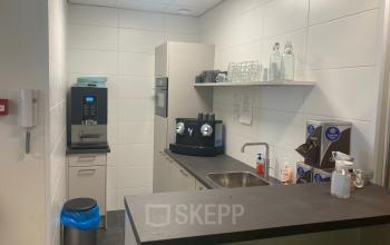 Compact pantry area in an office at Hoofdweg 66, Rotterdam Alexander, featuring a coffee machine, sink, and minimalist design.