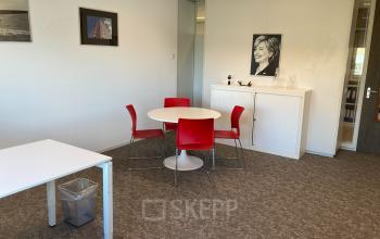 Modern office space with a round table and red chairs at Hoofdweg 66, Rotterdam Alexander; ideal for office space rental.