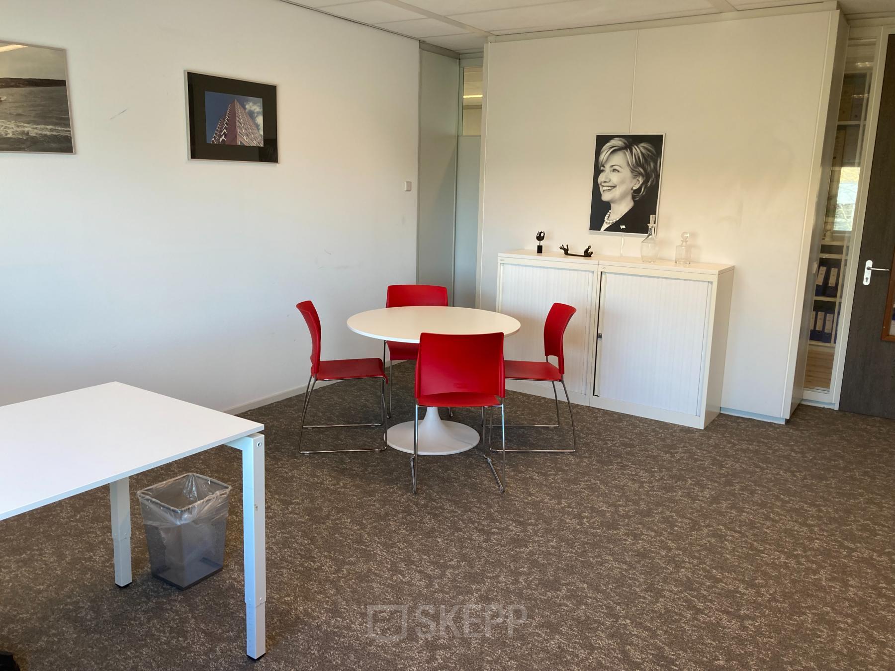 Modern office space with a round table and red chairs at Hoofdweg 66, Rotterdam Alexander; ideal for office space rental.