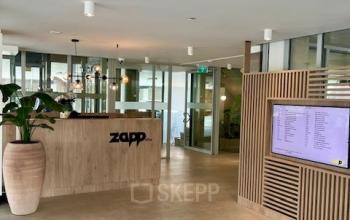 Reception area at Bahialaan 100, Rotterdam Brainpark with a modern design, ideal for office space rental featuring a sleek desk and digital display.