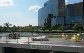 Modern office space rental at Bahialaan 100, Rotterdam Brainpark with outdoor seating overlooking a calm water feature.