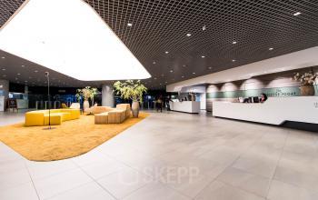 Spacious entrance of Weena 505 office building in Rotterdam Central Station with modern furnishings and reception desk, perfect for office space rental.