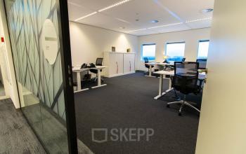 Modern office space rental at Weena 505, Rotterdam Central Station, featuring large windows, ergonomic desks, and spacious layout with natural light.