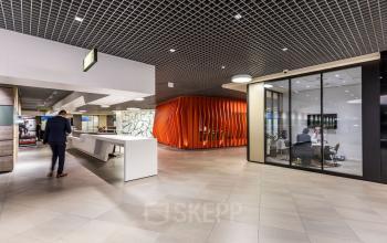 Modern office interior at Weena 505, Rotterdam Central Station with a sleek reception area and a conference room visible through glass walls.